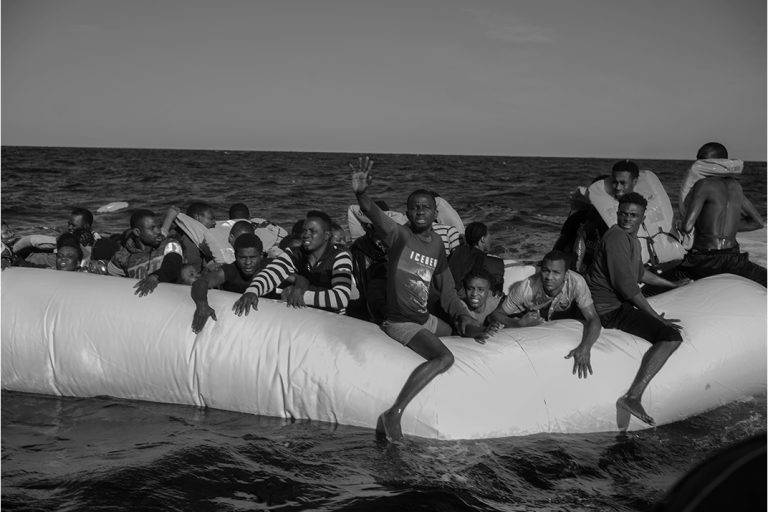 People in distress on a rubber boat just before being rescued at around 20 miles from the Libyan coast with 130 people on board. This Rubber boat left Tripoli the night of 26. An alert was launched by IMRCC ( Italian Maritime Rescue Coordination Centre) of Rome to Aquarius around 4 a.m. The rescue ship of Aquarius get the place around 9 a.m. The rescue operations last 4 hours. At the end of the day 89 people were saved among them 7 children from 15 days to 7 years old. Two women died on board of Aquarius and a third in Sfax in Tunisia where she was transport by an helicopter of Italian navy. 27 January 2018 International water Sicily Channel.