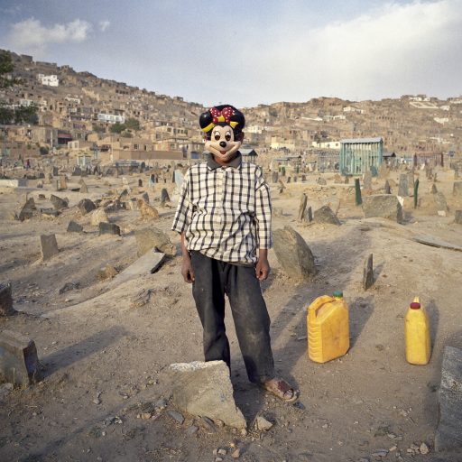 An Afghan boy is seen with a Minnie Mouse face mask in a local cemetery in Kabul, Afghanistan on Oct. 10, 2006. Afghan cemeteries are very basic: a single stone is used to mark the grave and very rarely something is engraved on it. After decades of war in Afghanistan, reconstruction in the country has slowly begun, though ongoing conflict continues to hinder the process. Despite the devastation and irregular water and electricity supply, Afghans struggle for a sense of normalcy.
