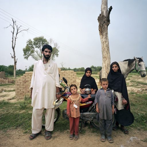 Man with his family and their personal belongings in North Western province in Pakistan on October 1, 2009.
" I've (Ali ur Rahman) put my kids on my motorcycle along with cooking plate and this tea pot and we left our home in Swat in the middle of the night, and that's it, everything else is left behind, we didn't even close the doors of our homes." 	
Portraits of internally displaced persons who fled the federally administered tribal area due to heavy fighting between Pakistani security forces and the Talibans. Tribal area was funded during the British rule of India as a buffer zone between volatile Afghanistan and India. Pakistan inherited the tribal area on a long term lease base. Tribal area is largely populated by ethnic Pashtuns and it is mostly beyond control of Pakistani government. During Soviet invasion of Afghanistan tribal area was a safe heaven for mujaheedins fighting Russians and a launching pad for US assistance to Afghani resistance to occupation. It was also a place where Taliban movement was born in the 90's. Now the Taliban turned against the Pakistani government resulting in heavy military operations and massive exodus of civilians creating one of the larges refugee crisis in recent history. These people were forced to leave their homes on short notice, often in the middle of the night. The treat was coming both from the Taliban repression and military indiscriminate bombing. They managed only to save the few personal belongings they could carry with themselves. Only the few licky ones had the means, the vehicles to leave notorioulsy poor and undeveloped tribal area with a bit more then just clothes and religious books.
(photo by Ziyah Gafic / VII network)